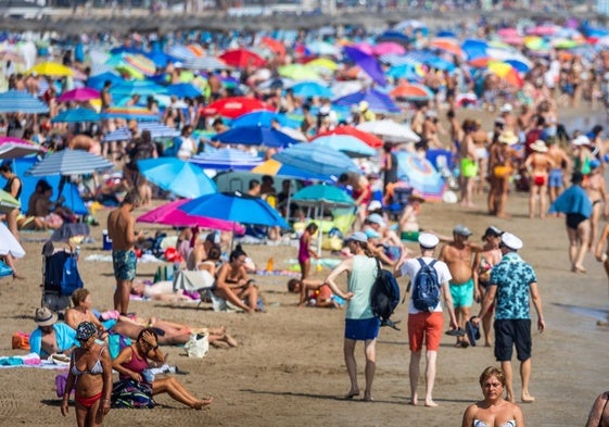 Un grupo de turistas busca una parcela de arena en la playa de la Malvarrosa.