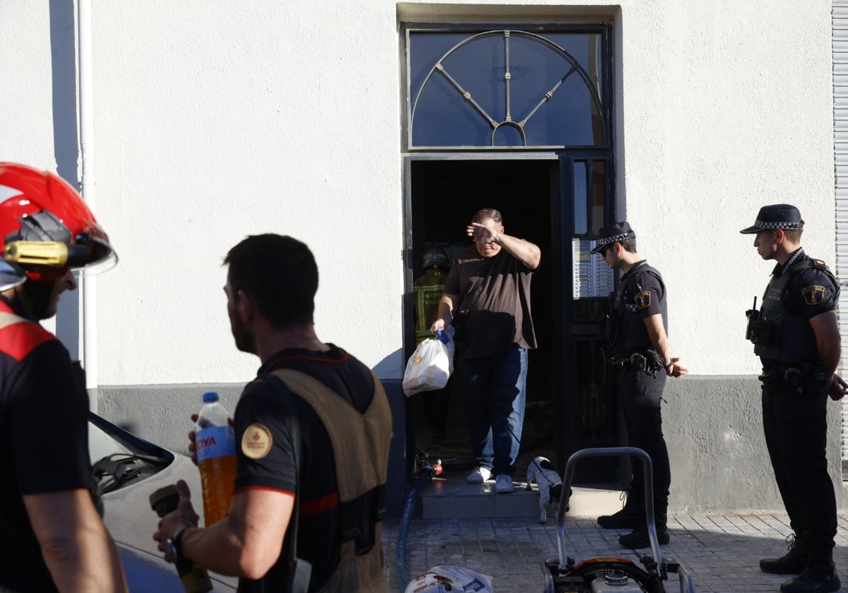 Varios policías locales y bomberos en la puerta del edificio donde de produjo el incendio.