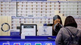 Una mujer compra un décimo en una administración de Lotería.