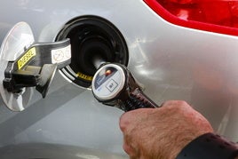 Un conductor llena el déposito de combustible.