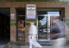 Dos viandantes pasan por delante de un cartel de alquiler de viviendas.