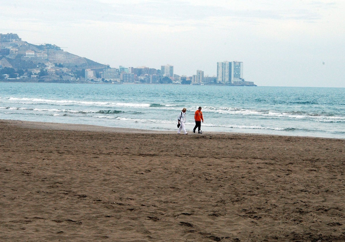 Dos personas pasean por la playa de Cullera.