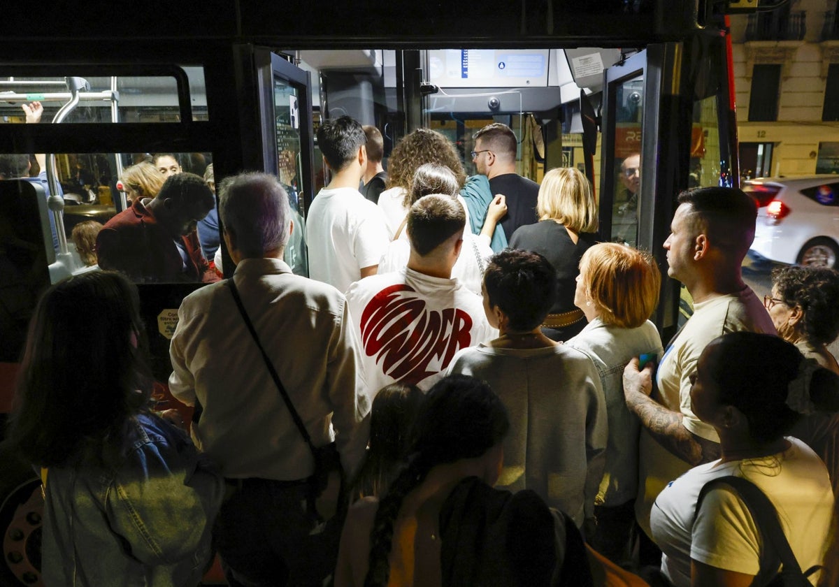 Varias personas se lanzan en masa a la entrada de un autobús detenido en una parada de la calle Xàtiva, el sábado 19 de octubre, en Valencia.