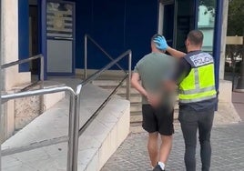 Un agente de la Policía Nacional traslada a uno de los presuntos estafadores hasta la Jefatura Superior de Valencia.