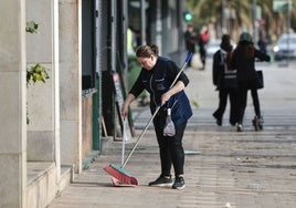 Una mujer limpia una calle comercial.