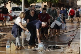 Vecinos de Paiporta recogen agua de la calle ante la falta de suministros.