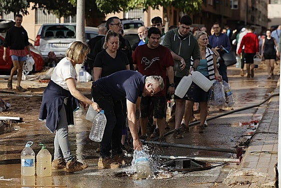 Vecinos de Paiporta recogen agua de la calle ante la falta de suministros.