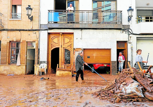 Varias personas limpian una calle de Paiporta.