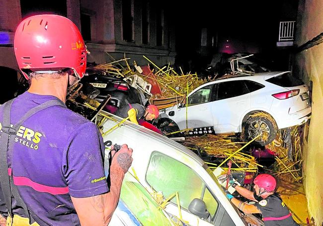 Dos bomberos juntoa a coches amontonados.