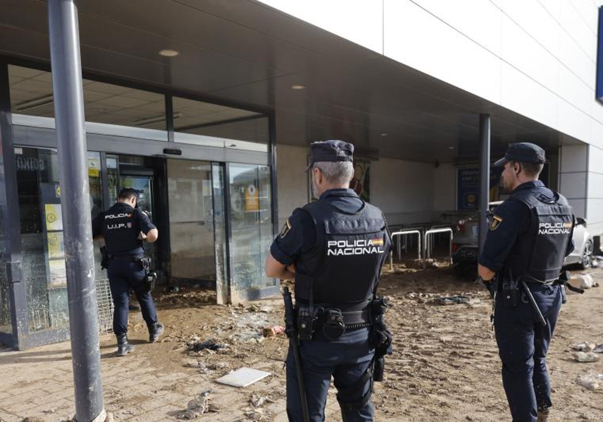 Agentes de la Policía Nacional vigilan un comercio en Alfafar para evitar saqueos.