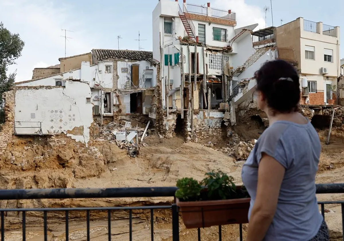 Una vecina observa un edificio derruido en Chiva.