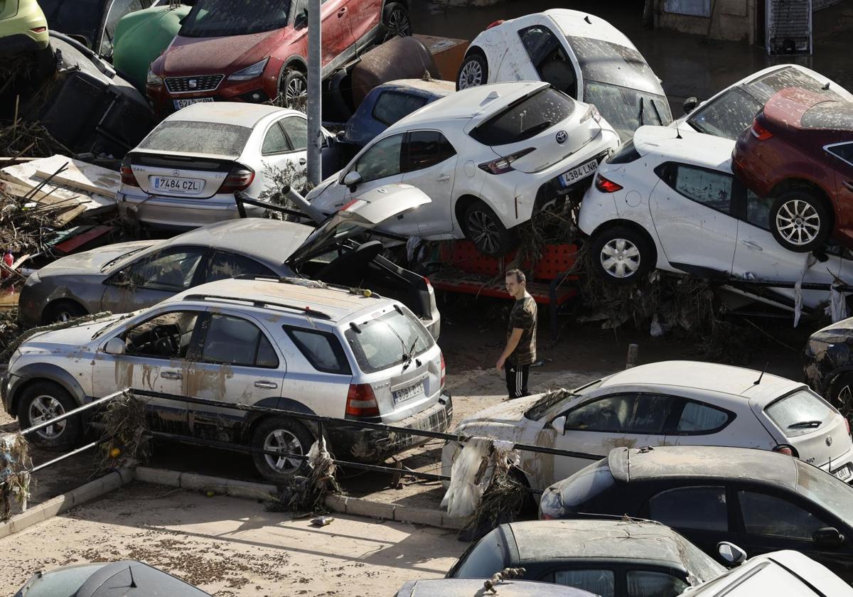 Un hombre camina entre los coches amontonados en una calle en Paiporta tras la DANA.