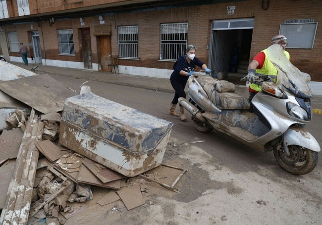 Dos personas empujan una moto en Guadassuar.