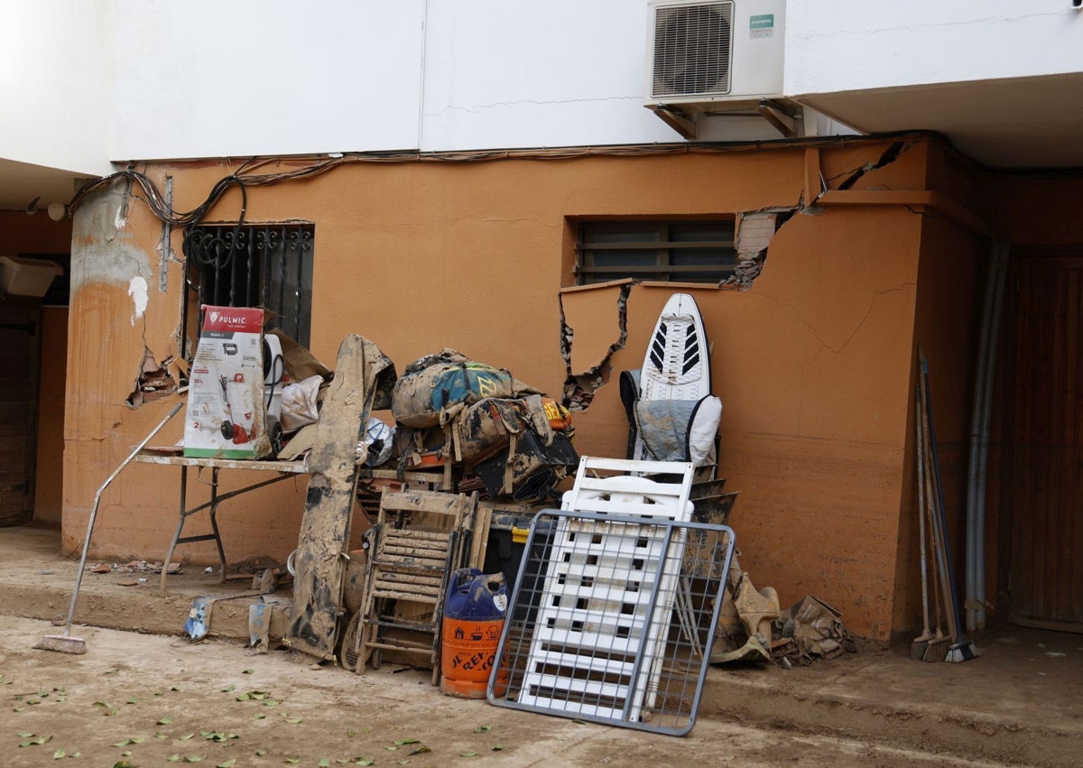 Imagen secundaria 1 - Fachada exterior de los adosados con grietas y enseres que han rescatado de las casas en Catarroja.