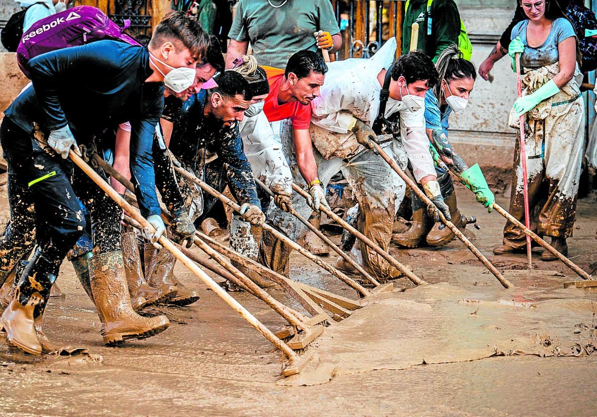 Varias personas trabajan juntas para eliminar el fango de las calles.