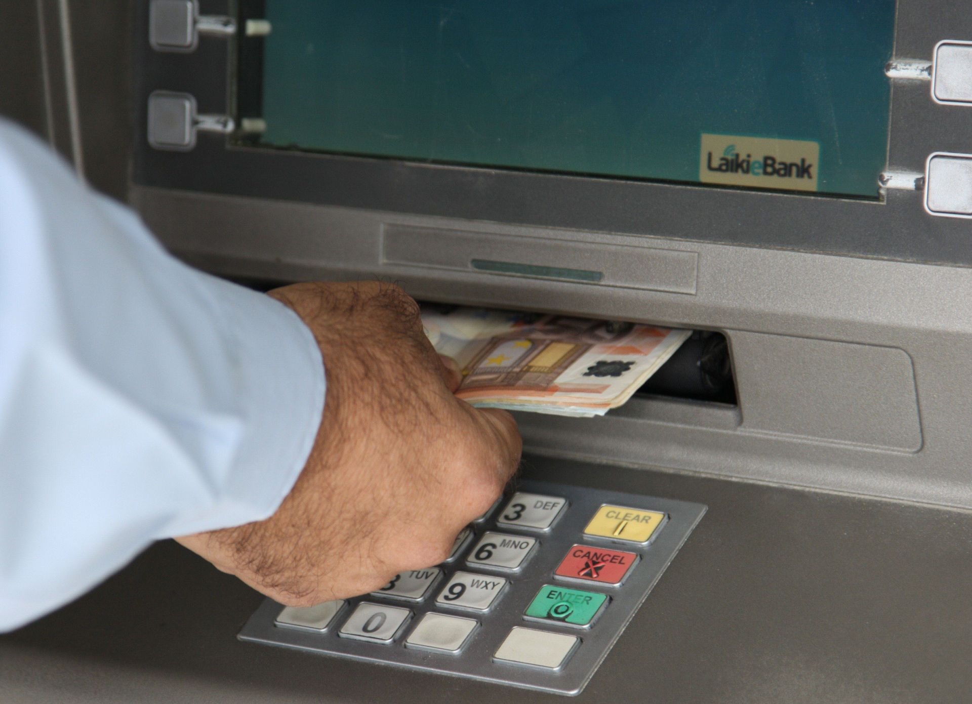 Un hombre saca dinero de un cajero autómatico de una sucursal de banco.
