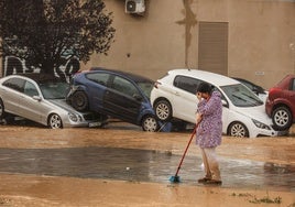 Una mujer barre en La Torre tras la inundación por la DANA.