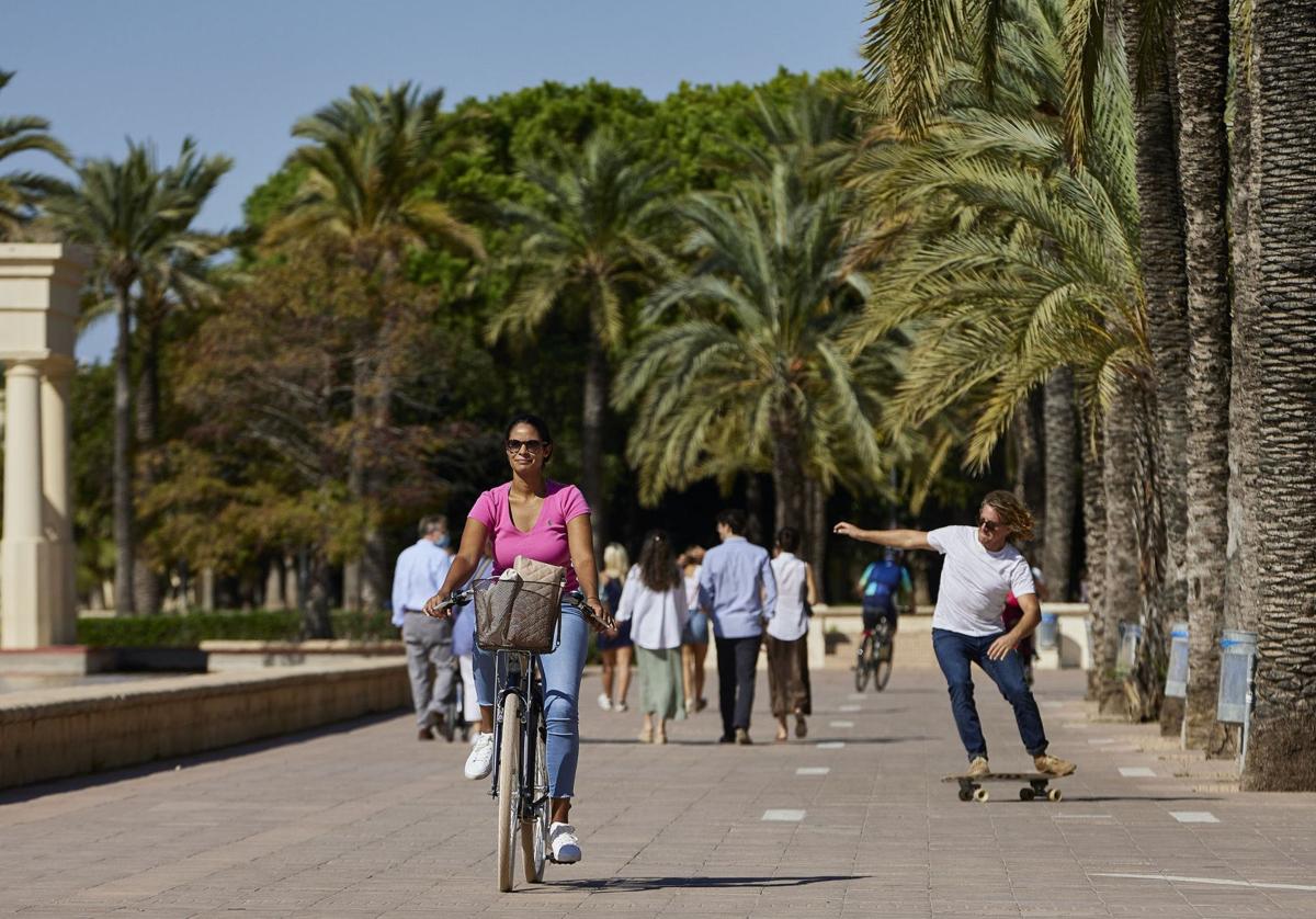 Gente paseando y montando en bicicleta por el cauce del río Turia en Valencia.