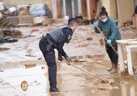 Un Policía Local de Valencia ayudando a una vecina a retirar el barro.