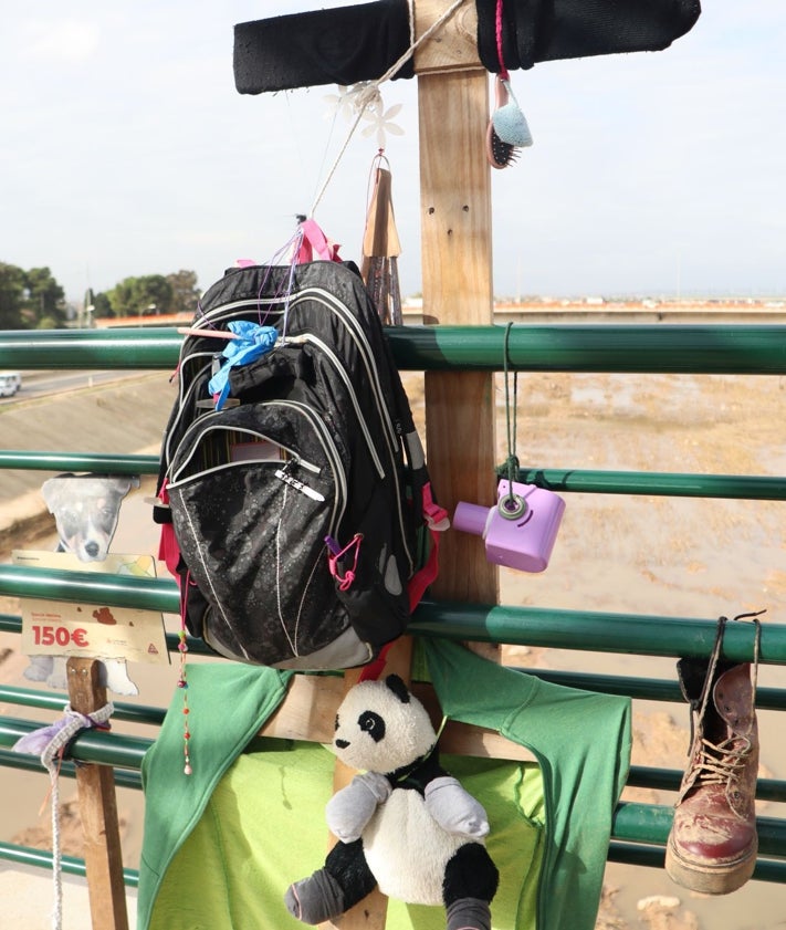 Imagen secundaria 2 - Cruces decoradas con ropa, botas y un peluche, en la pasarela que salva el río Turia.