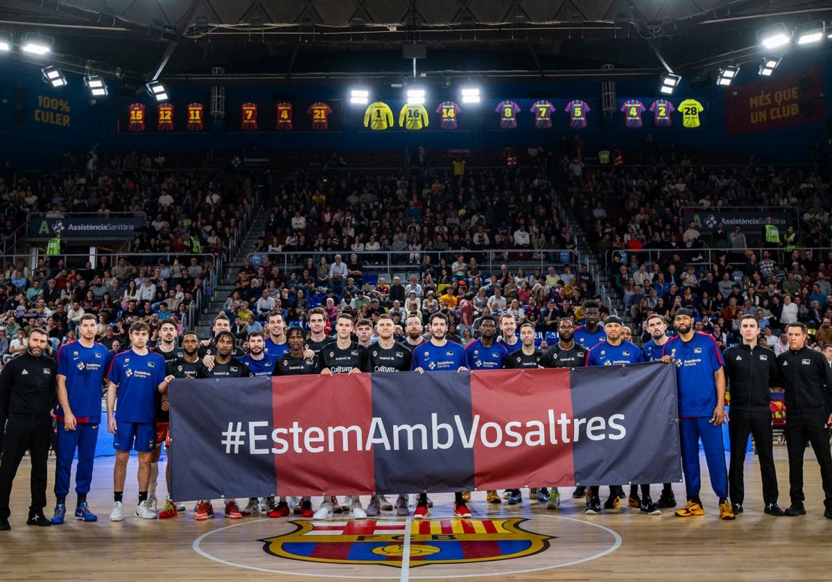 Los jugadores del Valencia Basket y el Barça, junto a los árbitros, posan con una pancarta de apoyo a las víctimas por la DANA.