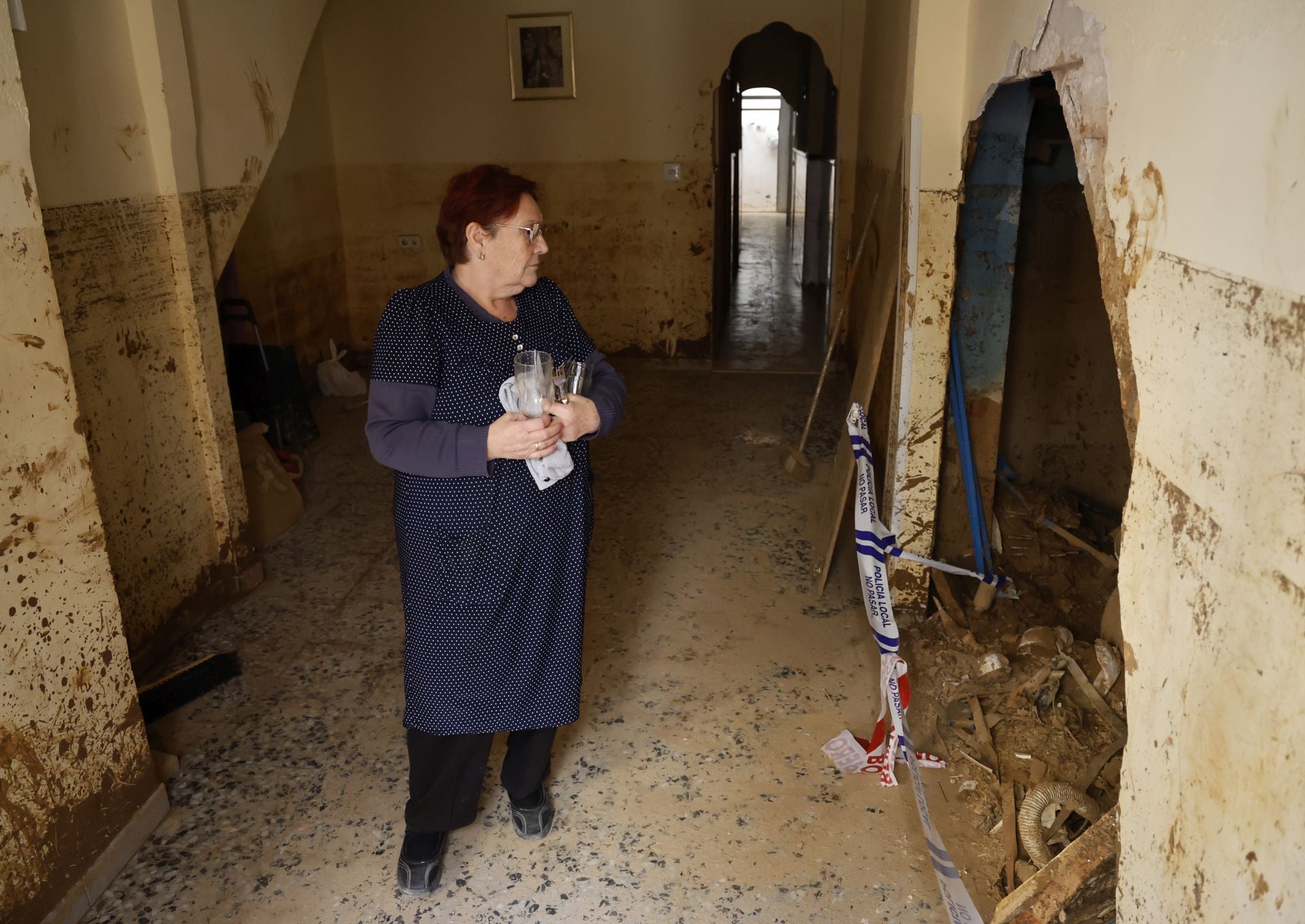 María Reche observa el gran boquete que se ha abierto hacia la vivienda contigua.