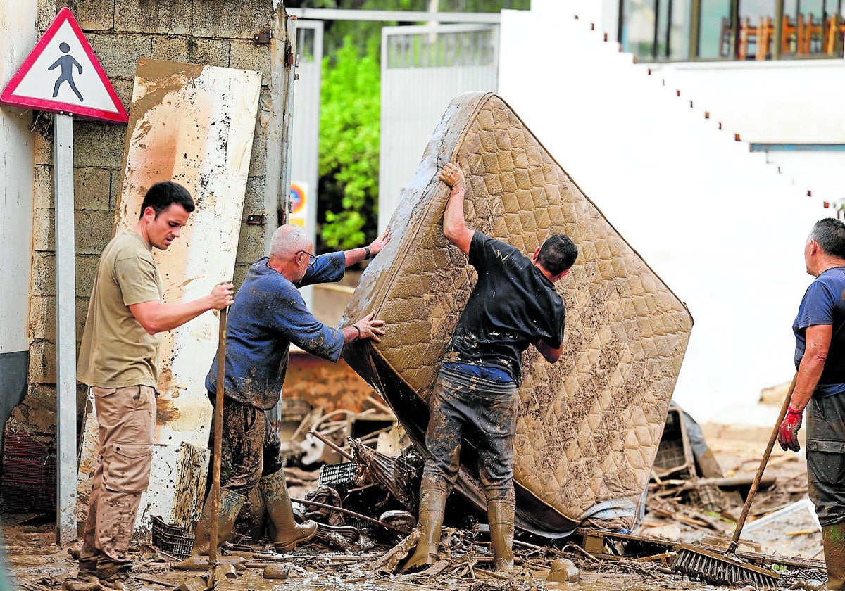 Vecinos sacan a la calle enseres dañados por las inundaciones en la localidad malagueña de Benamargosa.