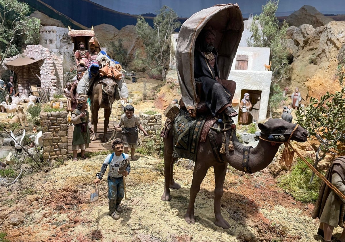 Imagen principal - Voluntario de la DANA junto a los Reyes de Oriente, pesebre con la rosa blanca y palas apoyadas en un escenario del belén.