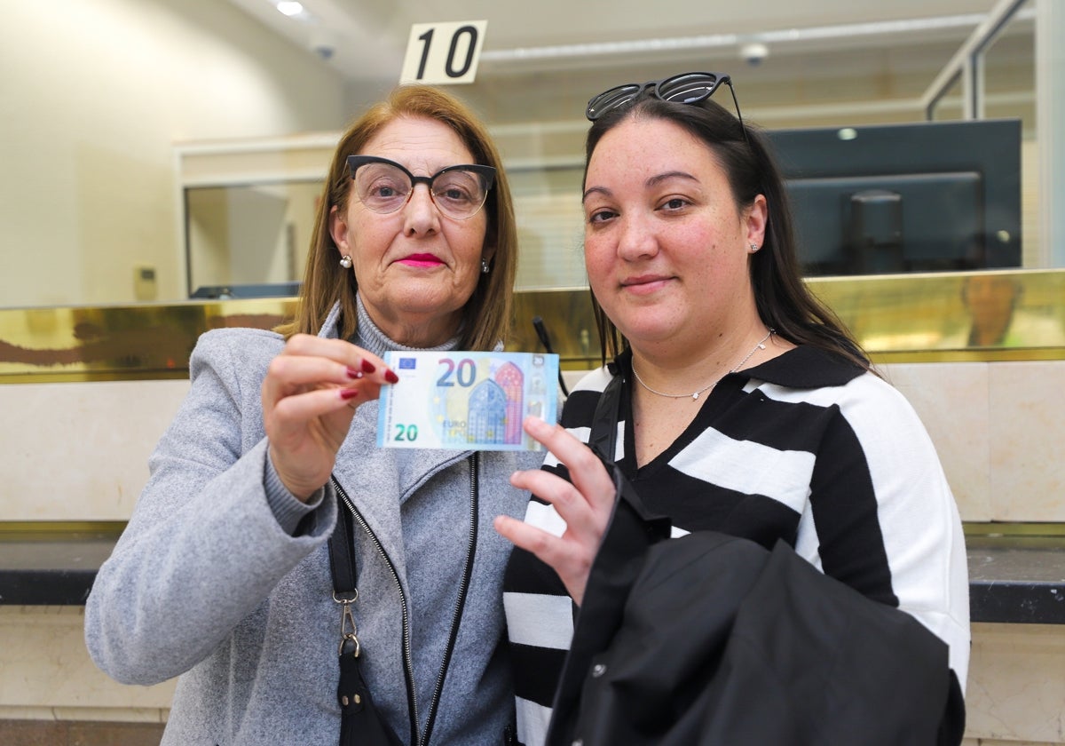 Isabel y Jenifer, con el billete nuevo que canjearon por el suyo, dañado al paso de la DANA por Paiporta.