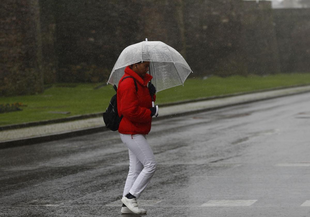 Una mujer circula por la calle durante un temporal de frío y lluvia, en una imagen de archivo.