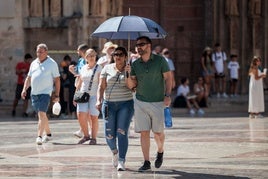 Dos turistas se protegen del sol en pleno verano en Valencia.