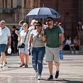 Dos turistas se protegen del sol en pleno verano en Valencia.