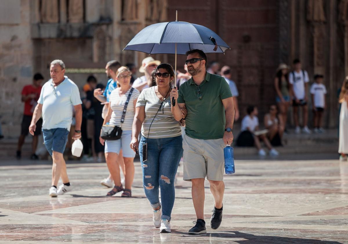 Dos turistas se protegen del sol en pleno verano en Valencia.