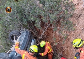 Bomberos junto al vehículo despeñado en un barranco de Chelva.