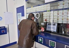 Un hombre compra un décimo en una administración de lotería.