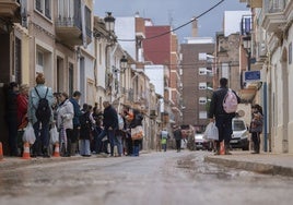 Vecinos en una calle embarrada afectada por la DANA.