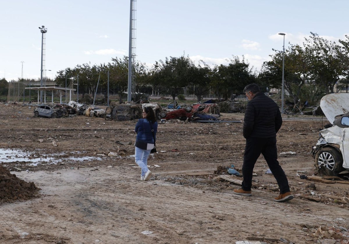 Dos personas caminan por el campo de fútbol de Alfafar, destruido.