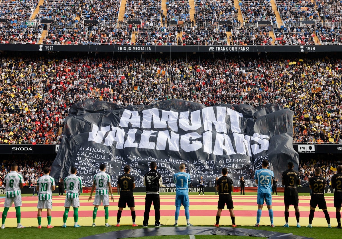 Los jugadores del Valencia y Betis observando la pancarta en apoyo a los municipios afectados por la DANA