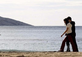 Dos jóvenes pasean por un playa de Benidorm.