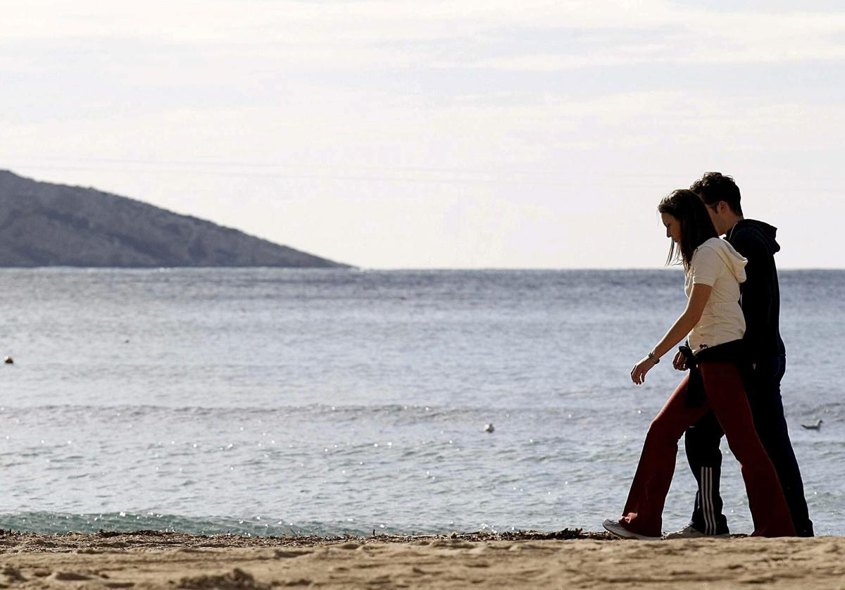 Dos jóvenes pasean por un playa de Benidorm.