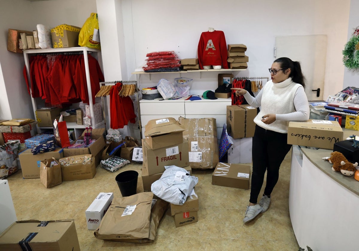 Carla, joven de Paiporta propietaria de la papelería L'Escola, junto a un montón de paquetes y regalos.