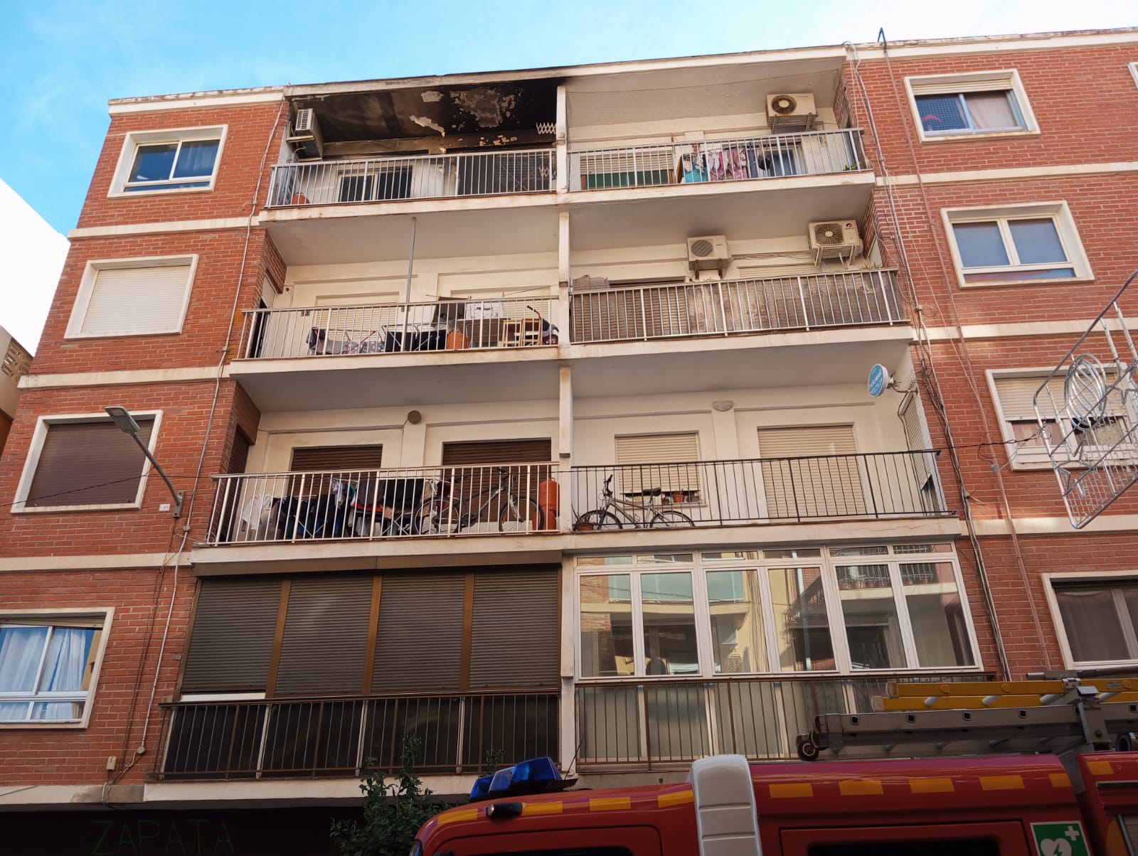 Arriba, la vivienda y edificio donde se ha producido el incendio.Abajo, expectación entre lo vecinos de la zona.