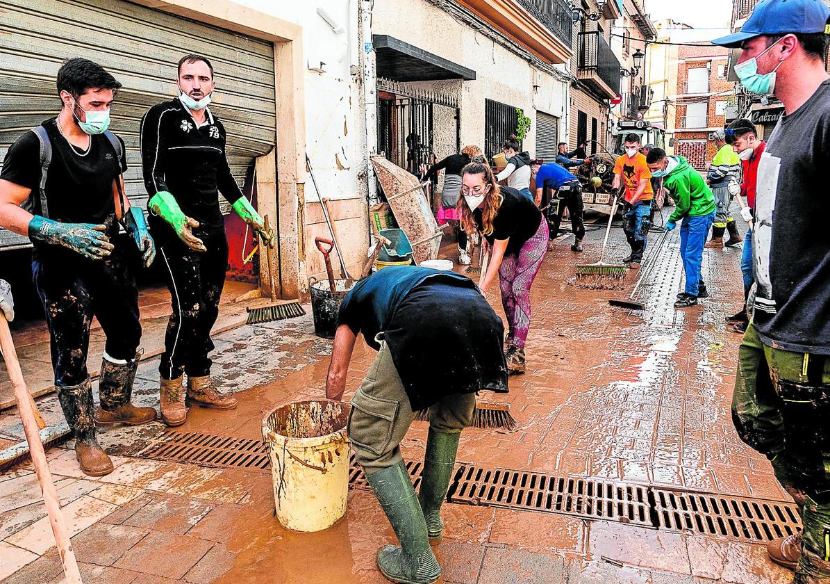 Varios vecinos de Chiva quitan barro y lodo.