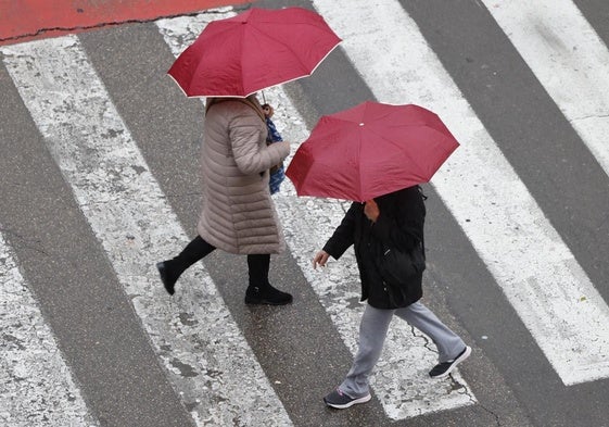 Dos peatones pasean con paraguas este martes en Valencia.