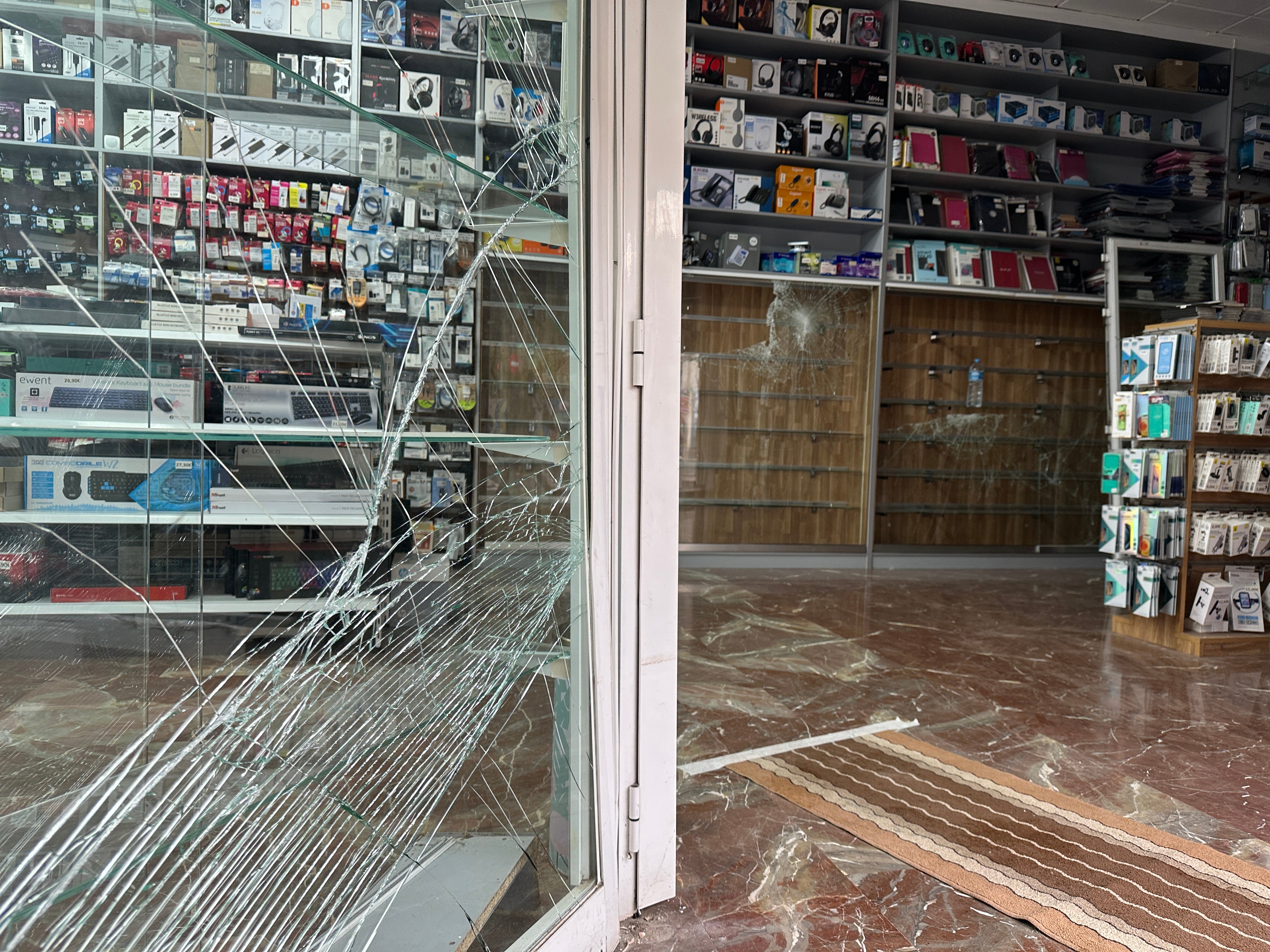 La puerta de la tienda asaltada, destrozada tras el robo.