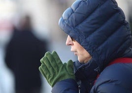 Una mujer se da calor en las manos.