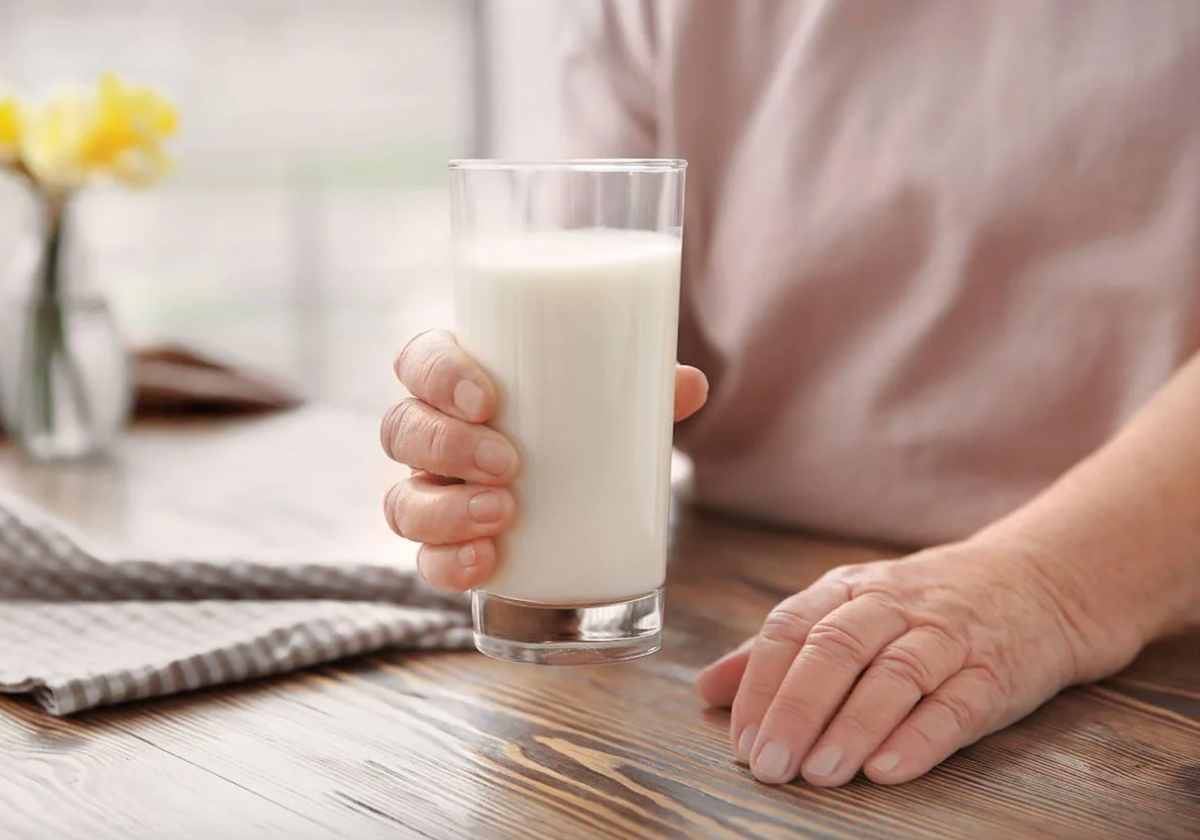 Una mujer sostiene un vaso de leche.