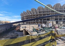 Dos trabajadores apilan sacos de cemento en una de las entradas de la obra del nuevo Mestalla.