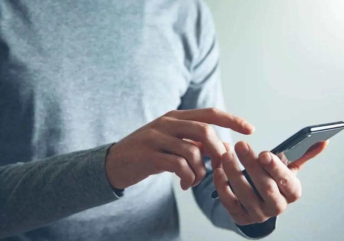 Un hombre revisa su teléfono móvil, imagen de archivo.