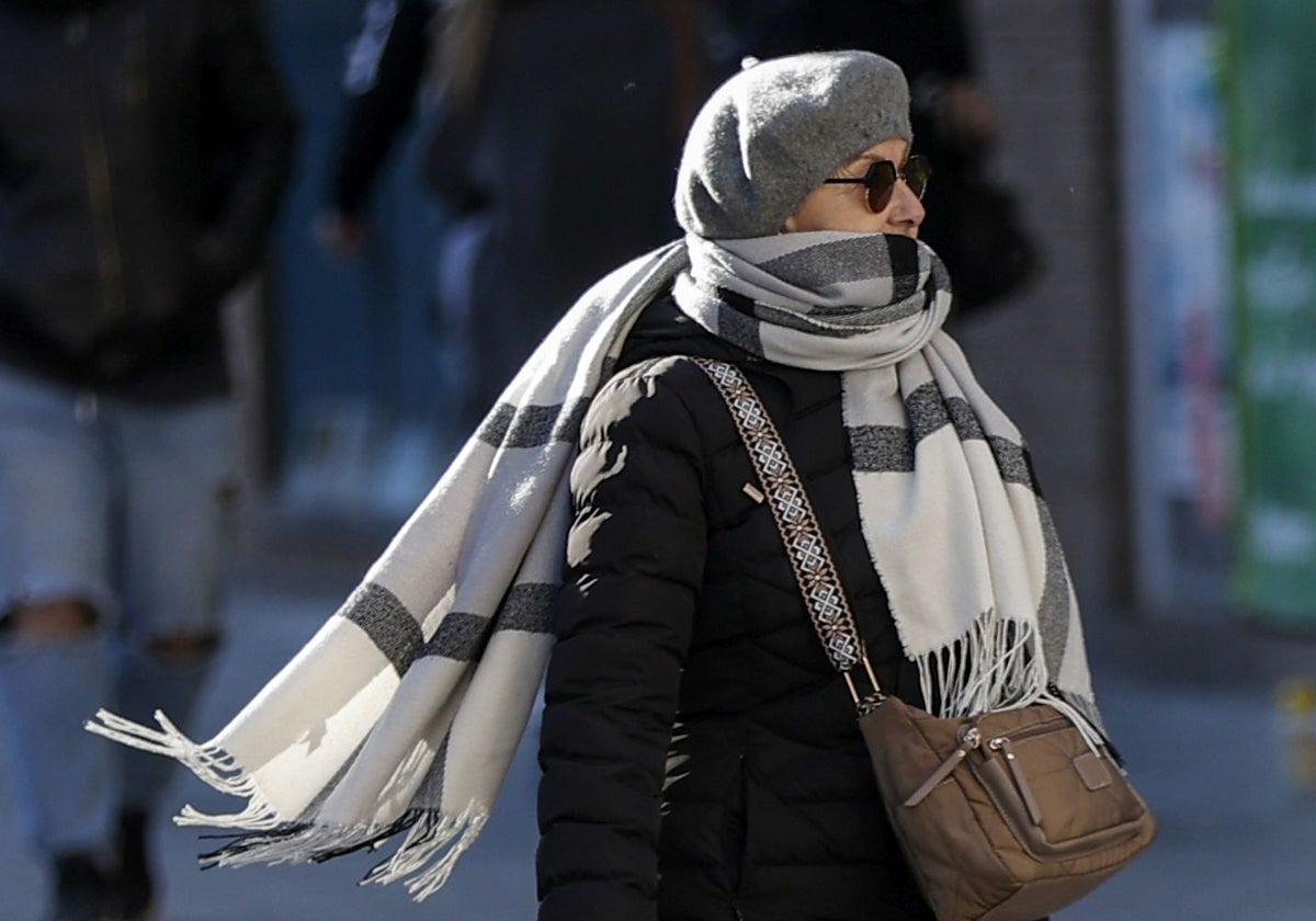 Una mujer se protege del frío por la calle.